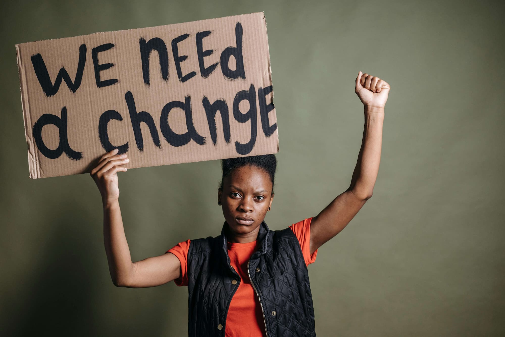 A person holds a sign that reads, "we need a change"